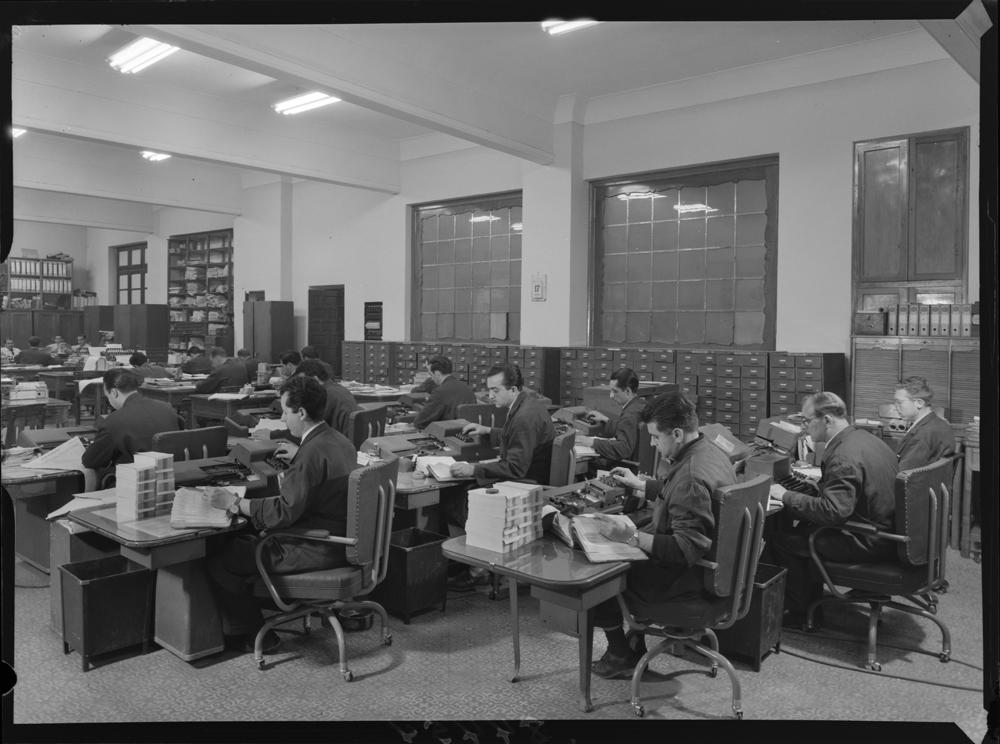 PANDO (1961) - Sala con trabajadores sentados frente a sus puestos de trabajo en el interior del palacio que albergó la sede de la Compañía Sevillana de Electricidad S. A.