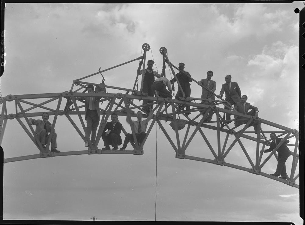 PANDO (1954) - Obras en Villaverde. Grupo integrado por once hombres subidos a una grúa de construcción con dos poleas en el centro.