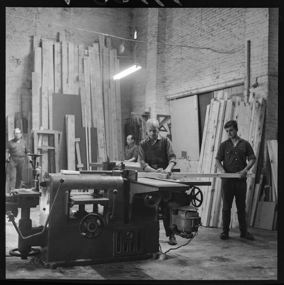 PANDO (1965) - Taller de carpintería. Trabajadores en el interior de un taller de carpintería con mesa de trabajo dotada de torno y sierra