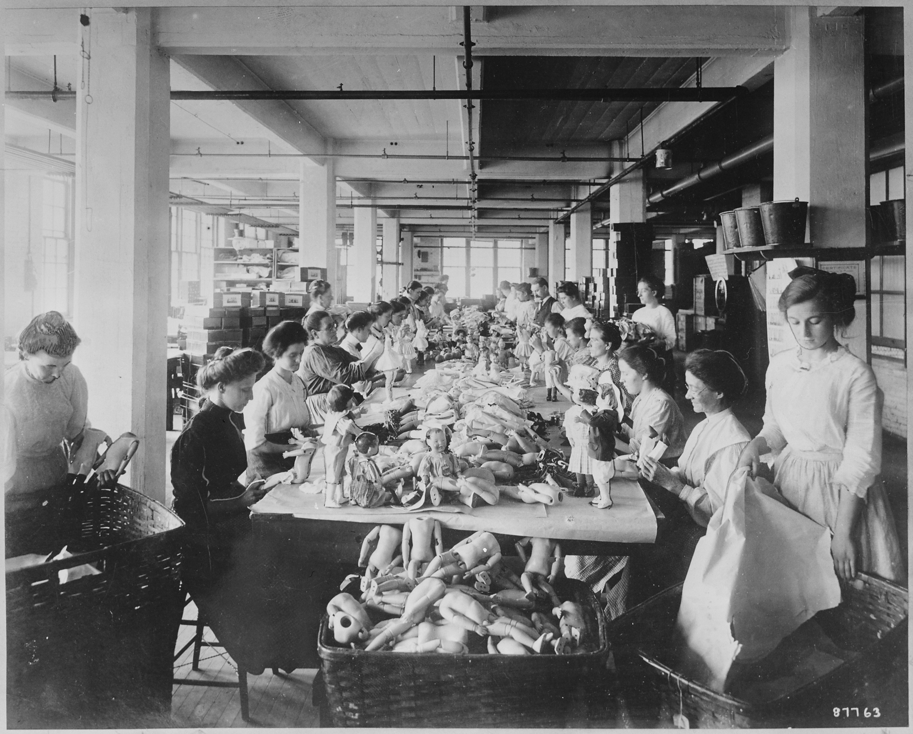 Women assembling dolls on a long worktable at the Shrenhat Toy Company, Philadelphia
